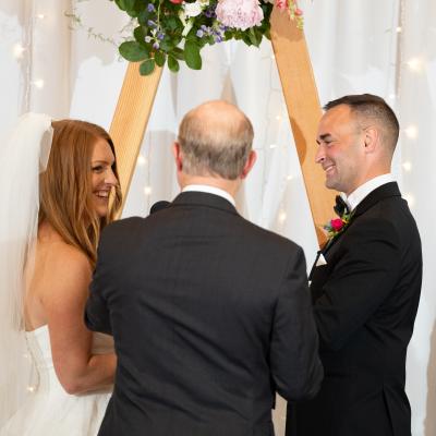 Bride and groom smiling at each other during their wedding ceremony.