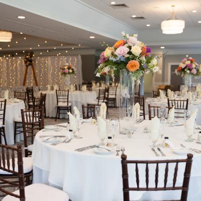 Elegant banquet hall with round tables, floral centerpieces, and soft lighting.