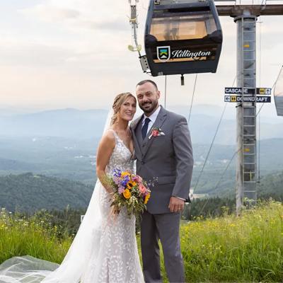 Bride and groom pose with mountain views and a ski lift in the background.