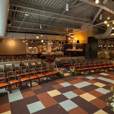 A spacious venue with rows of chairs, a stage, and decorative plants.