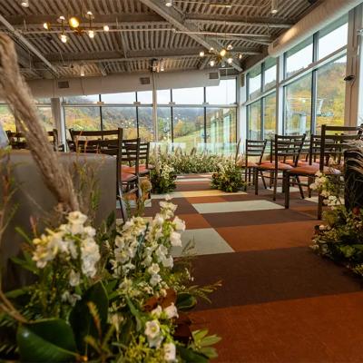 A decorated event space with floral arrangements and chairs facing a large window.