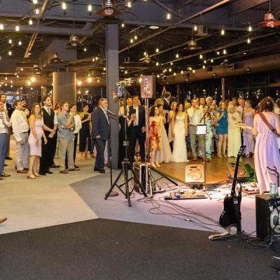 A lively event with guests dancing and a band performing under string lights.