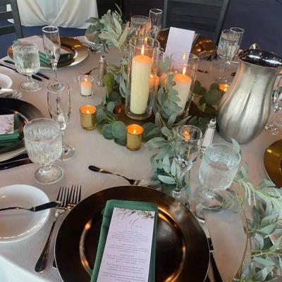 Elegant dining table set with candles, menus, and greenery accents.