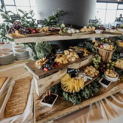 A decorative cheese and charcuterie spread on wooden trays with fruits and crackers.