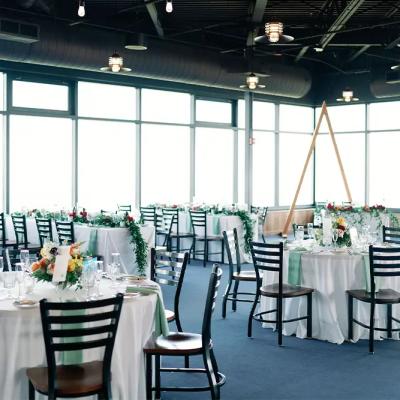 Elegant dining setup in a bright venue with tables, chairs, and floral centerpieces.