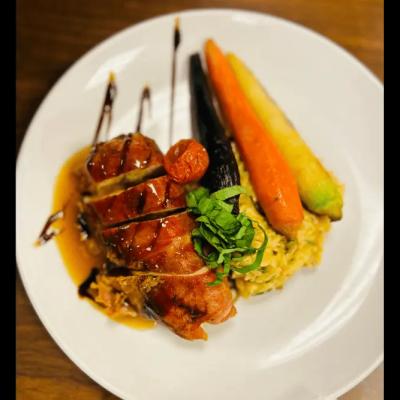 Grilled chicken with sauce, served with colorful roasted vegetables and rice.