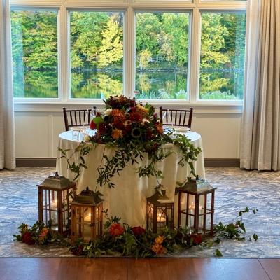 Elegant table with flowers and lanterns, overlooking a scenic outdoor view.