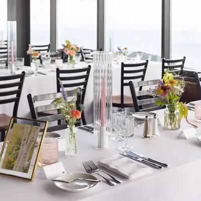 Elegant dining setup with floral centerpieces and city views through large windows.