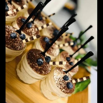 Dessert cups topped with cocoa, blueberries, and chocolate striped sticks.