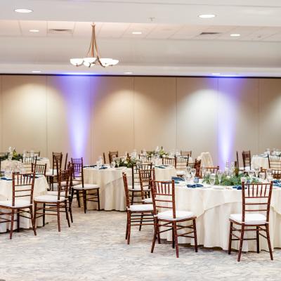 Elegant dining setup with tables, chairs, and decorative centerpieces in a spacious event room.