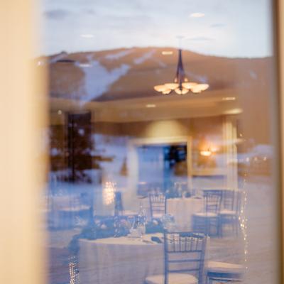 View of a banquet room with tables, chairs, and a mountain reflection at twilight.