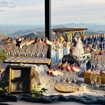 Wedding ceremony with scenic mountain backdrop and elegantly arranged glasses in the foreground.