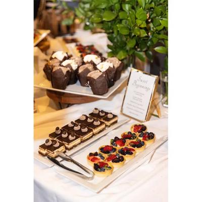 A dessert table featuring chocolate cupcakes, layered cakes, and fruit tarts.