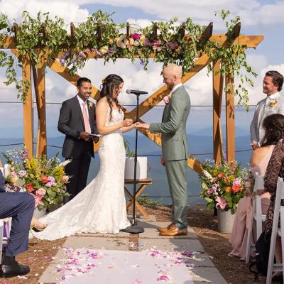 A couple exchanges vows at a scenic outdoor wedding with floral decor.