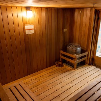 Interior of a wooden sauna with benches, a heater, and an exit door labeled 
