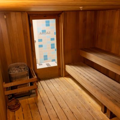Interior of a wooden sauna with benches and a door labeled 