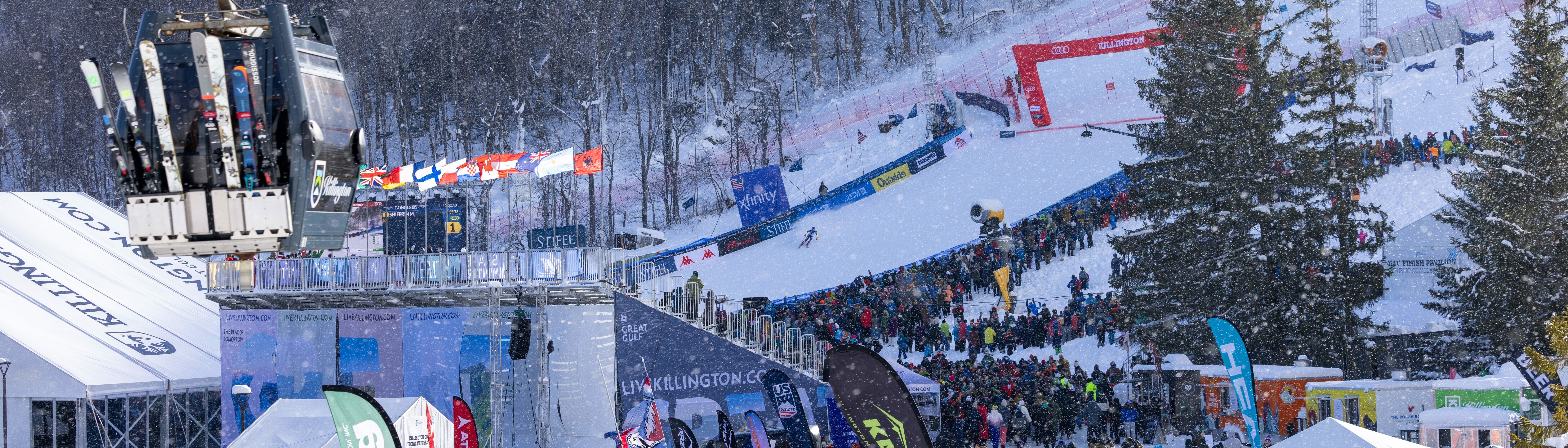 Ski slopes bustling with spectators amid a snowy backdrop and a ski lift above.