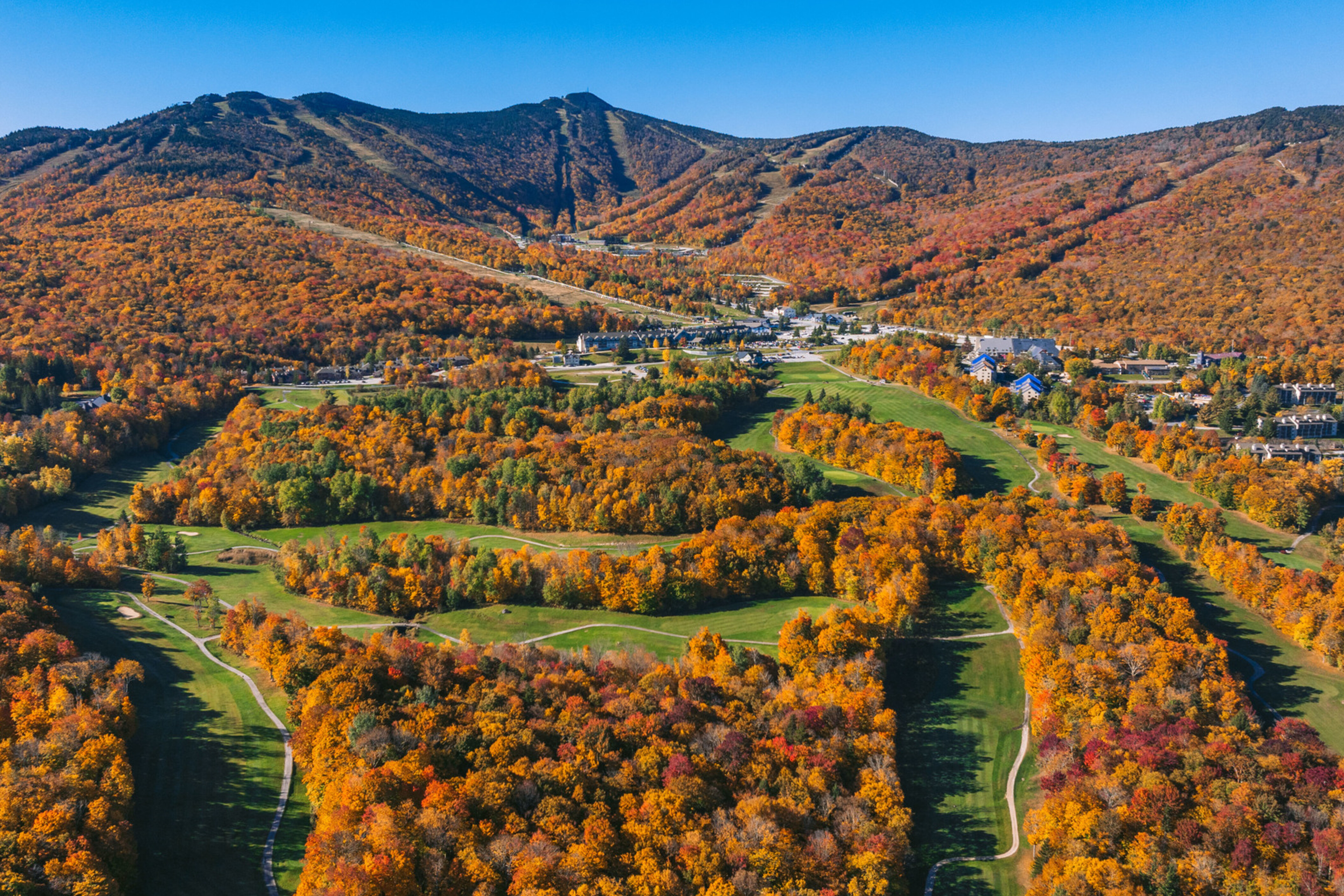 Aerial view of vibrant fall foliage surrounding a mountain resort.