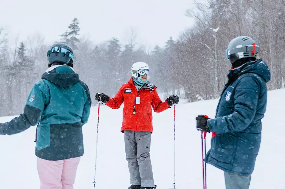 Three skiers in the snow converse during a snowy day on the slopes.