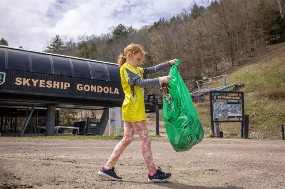 Girl in a bright shirt collecting trash near the Skyship Gondola station.