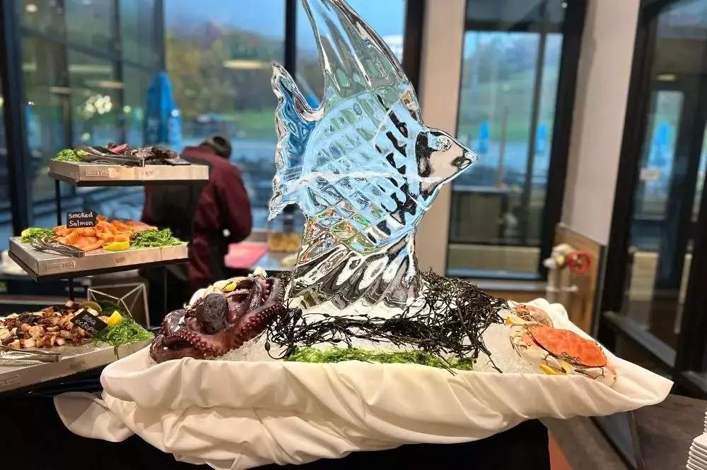 Ice sculpture of a fish with seafood platters displayed around it.