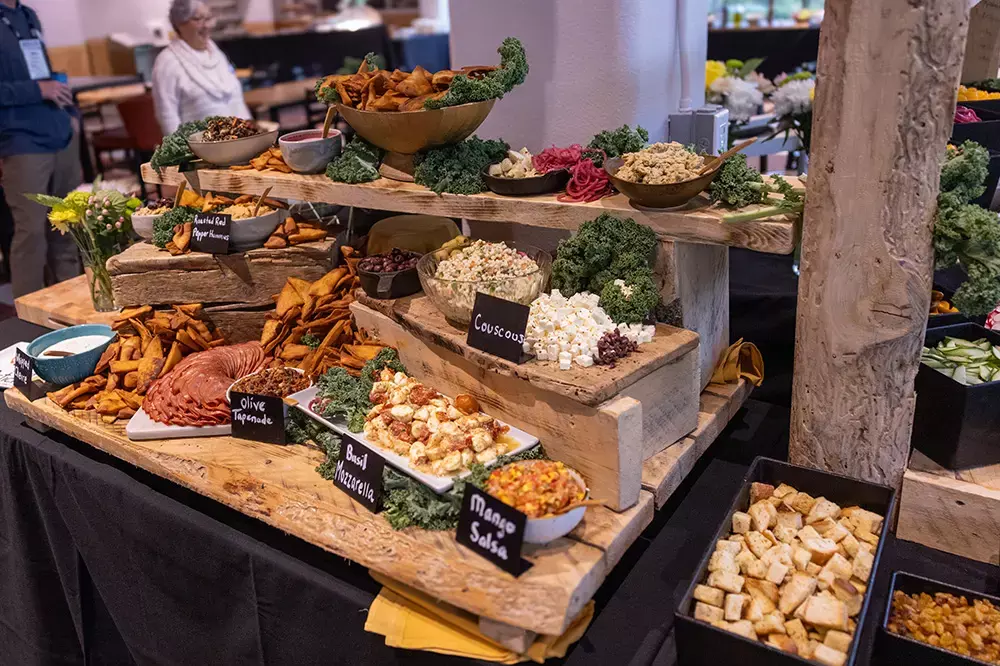 A buffet display featuring various appetizers, dips, and snacks on wooden serving trays.