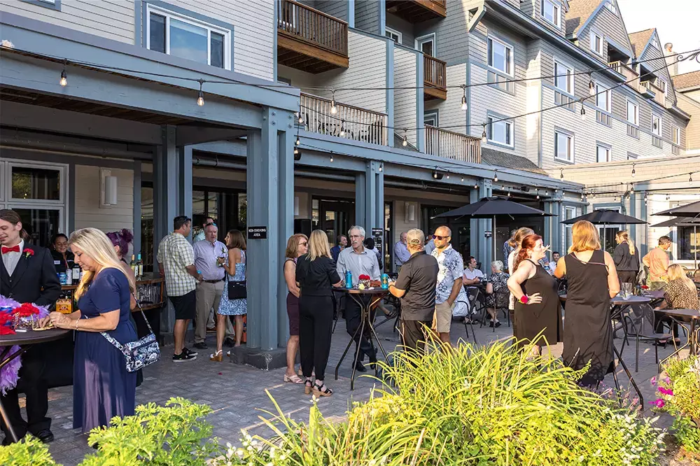A lively outdoor gathering at a venue, with guests socializing and enjoying drinks.