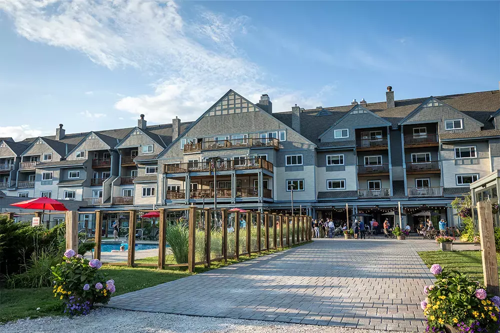 Resort building with balconies and a pool area, surrounded by greenery and flowers.