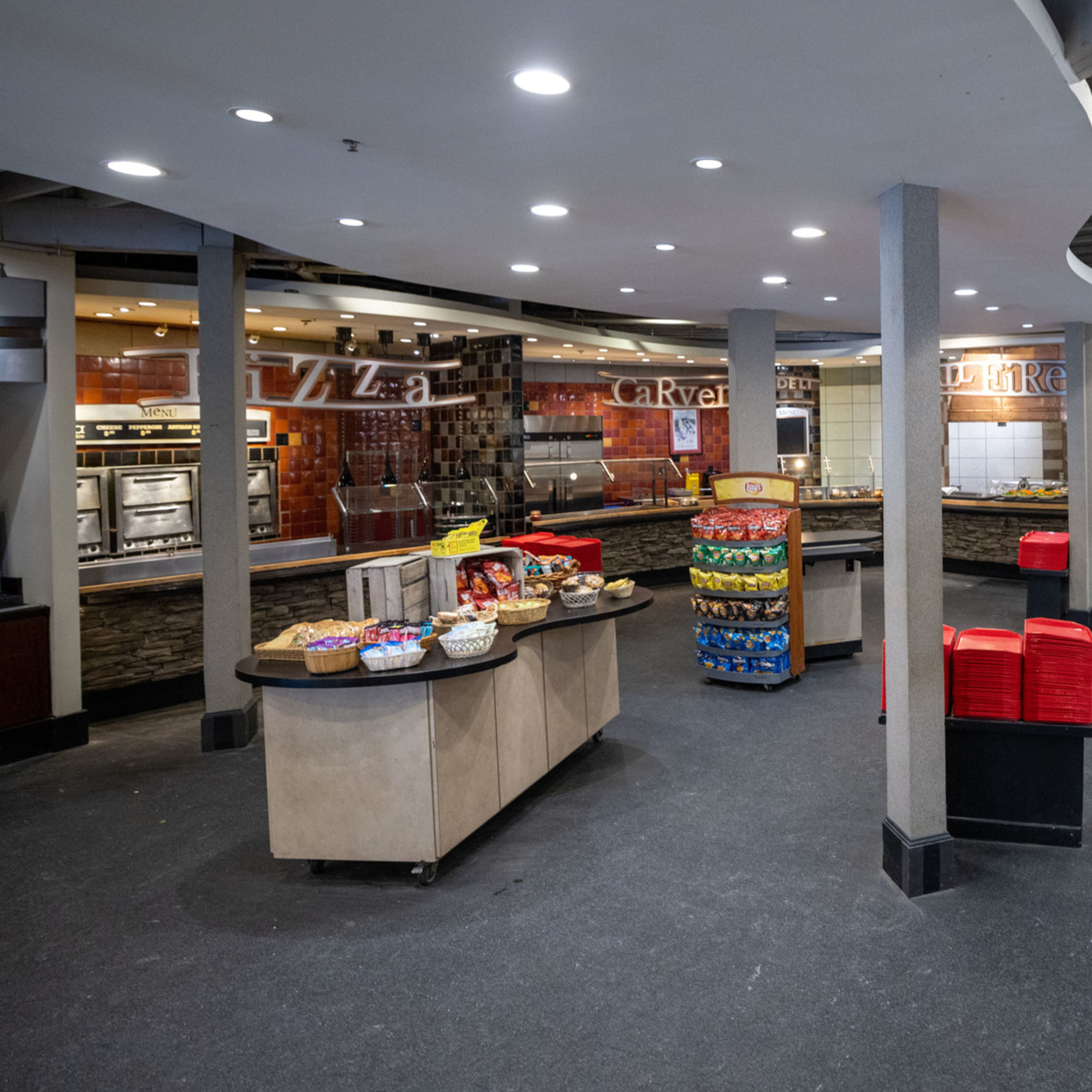An empty dining area with food stations labeled Pizza, Carvery, and Deli.