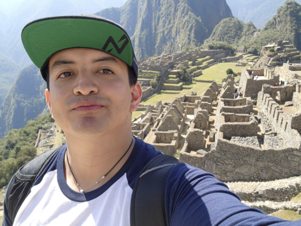 A person takes a selfie with Machu Picchu in the background.