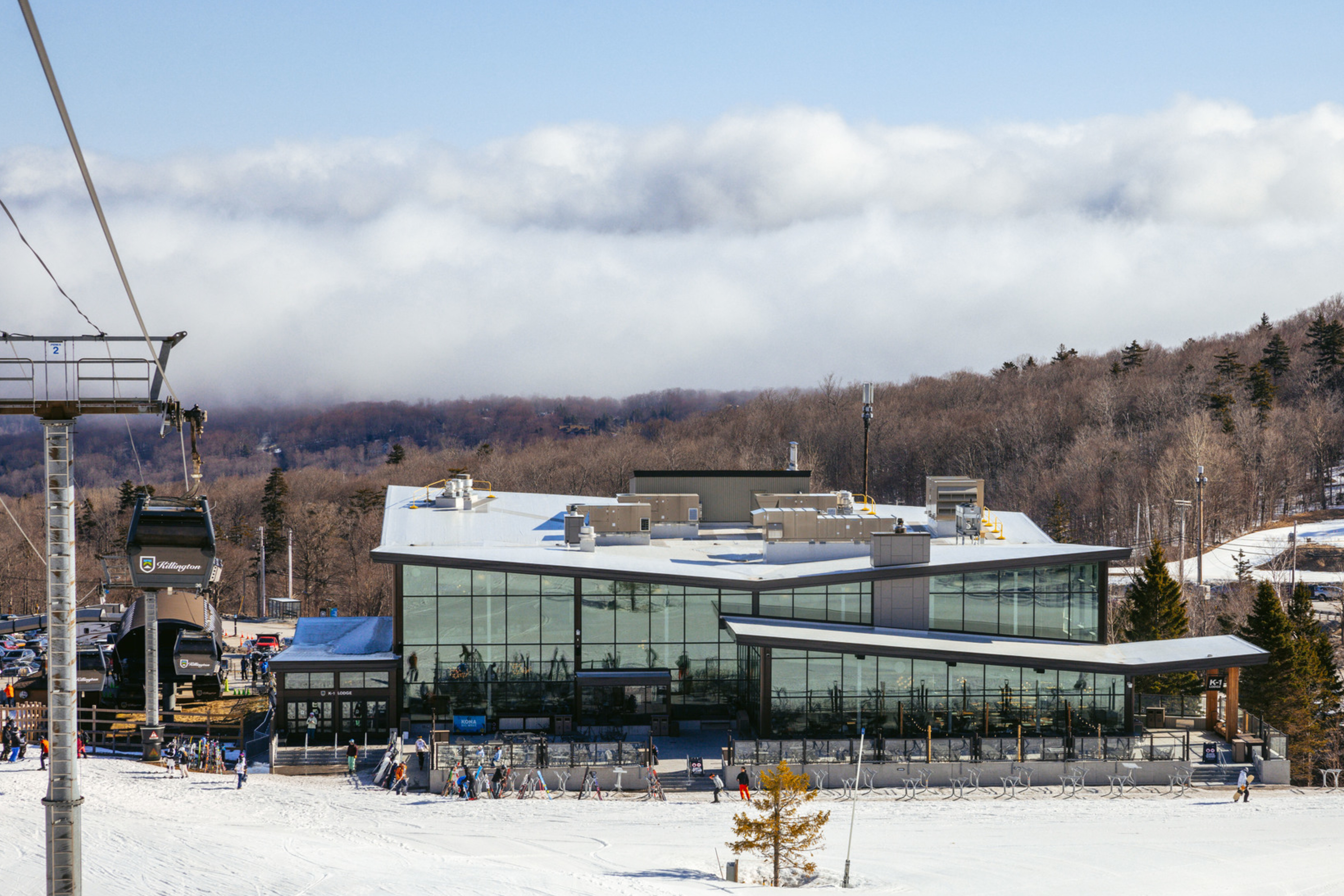Ski lodge with large glass windows surrounded by snow and a ski lift.