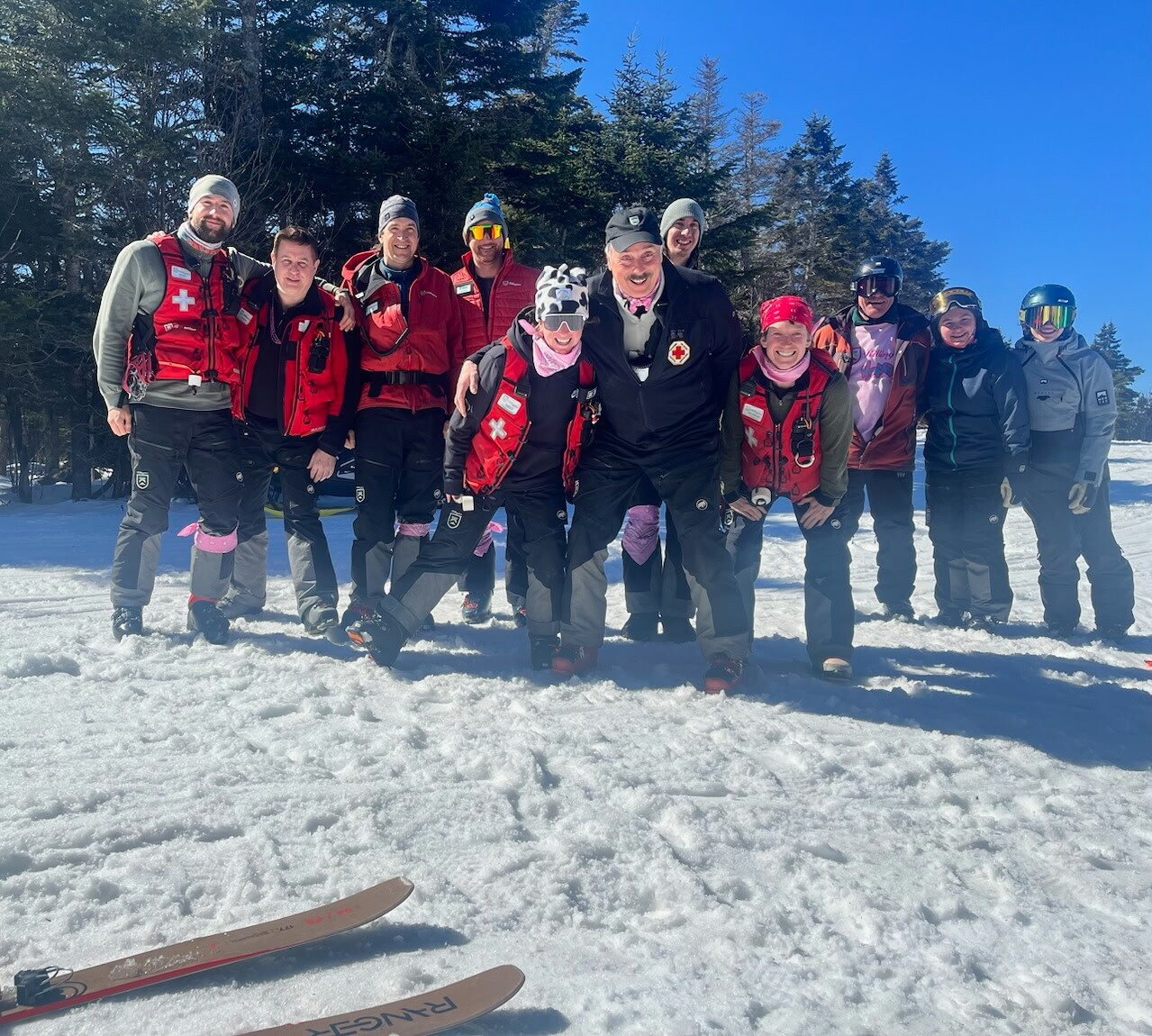 A group of ski patrollers pose together on snowy terrain.