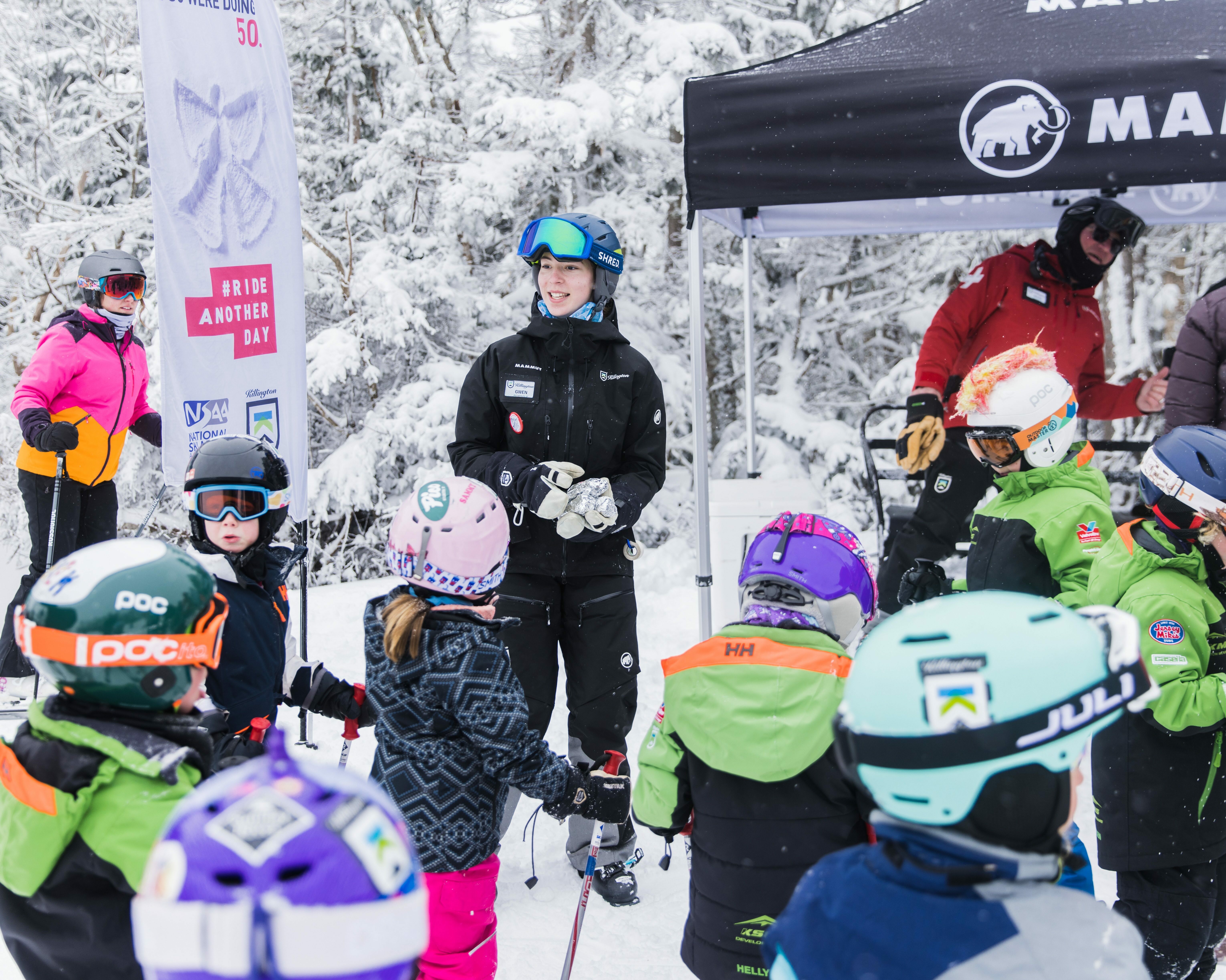 Ski resort employee guiding children in snowy landscape during a safety promotion event.