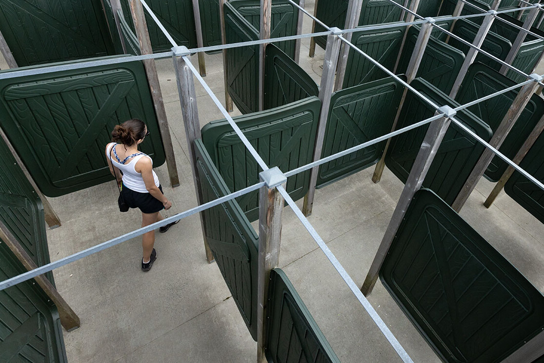 A woman navigates a maze made of green panels.