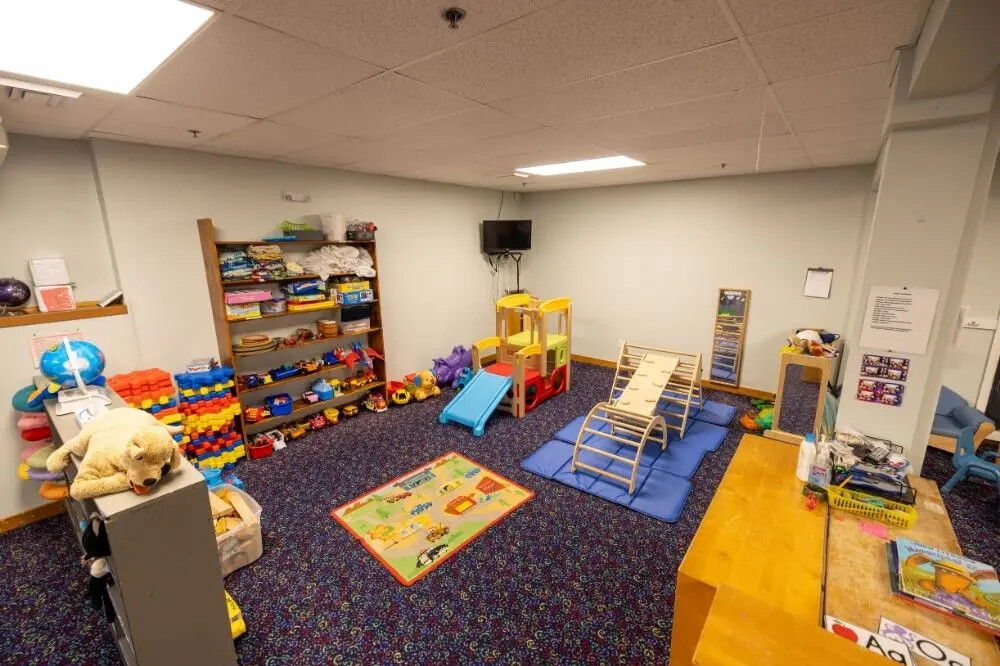 Brightly colored playroom with toys, slides, and climbing equipment.