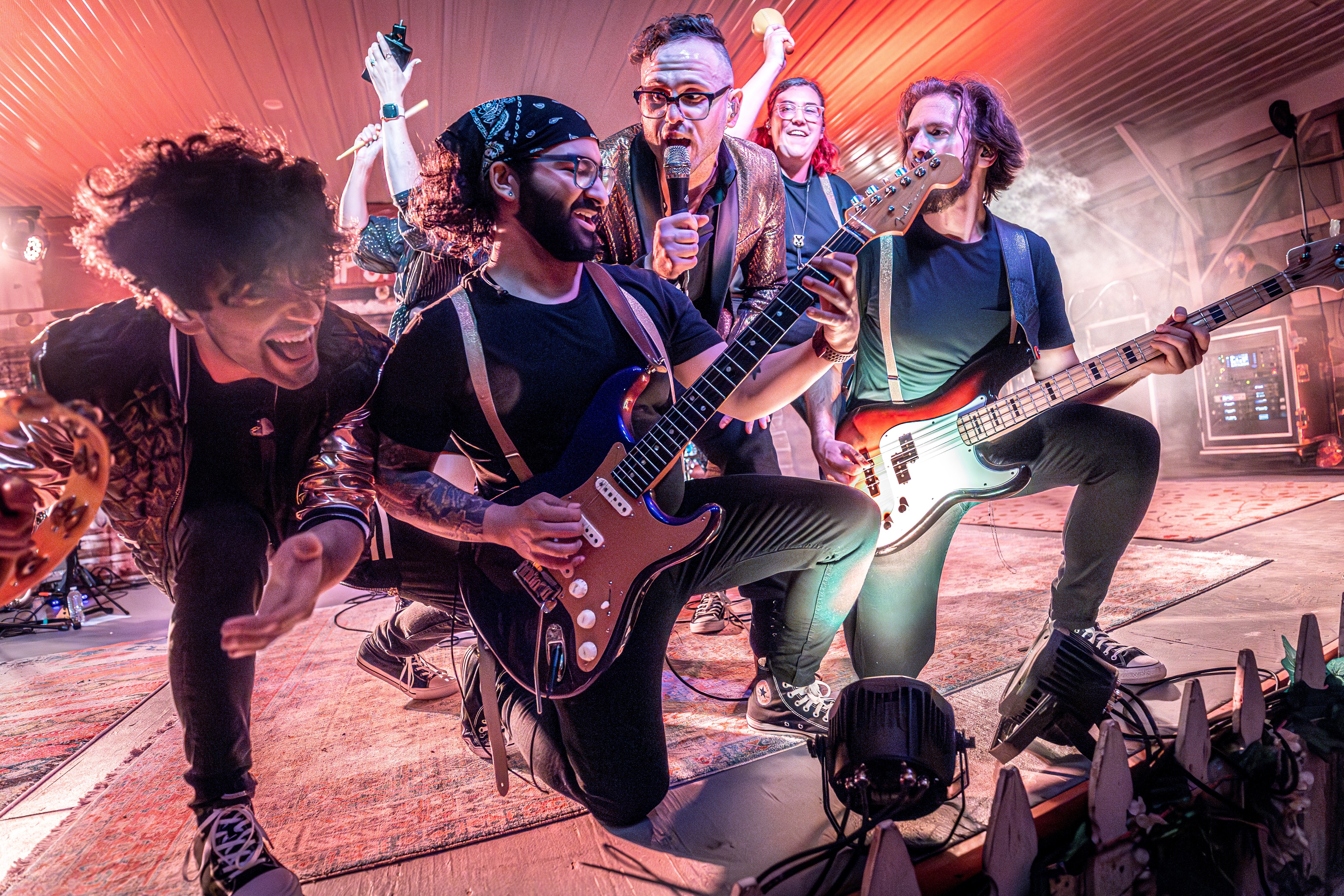 A lively band performs energetically on stage with instruments and joyful expressions.