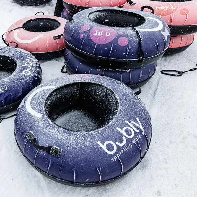 Colorful snow tube floats stacked, featuring logos and playful designs, in a snowy environment.