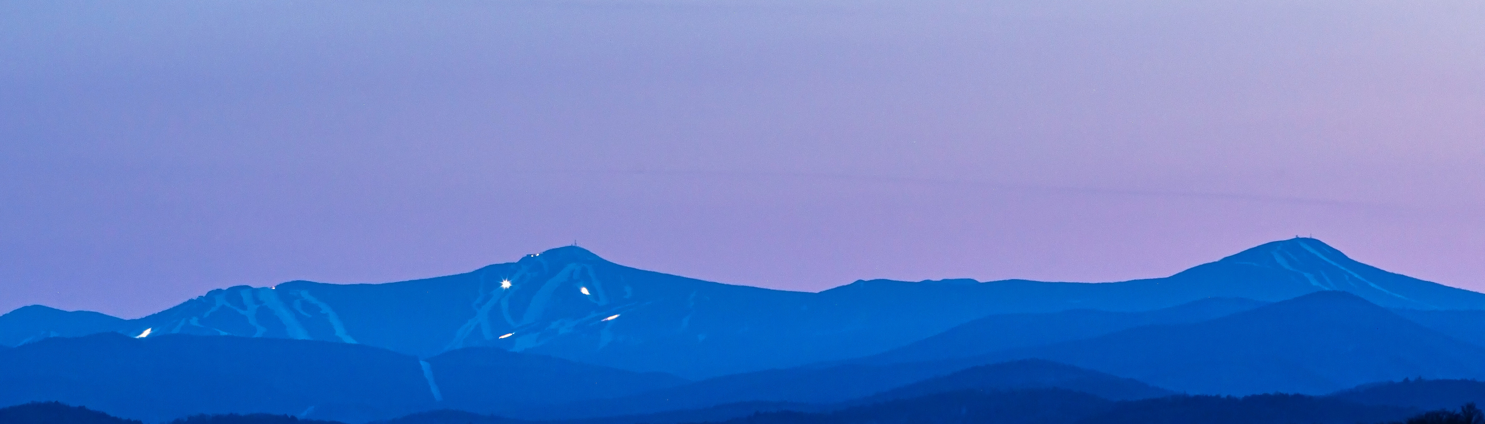 Silhouetted mountains against a soft purple sky at dusk.