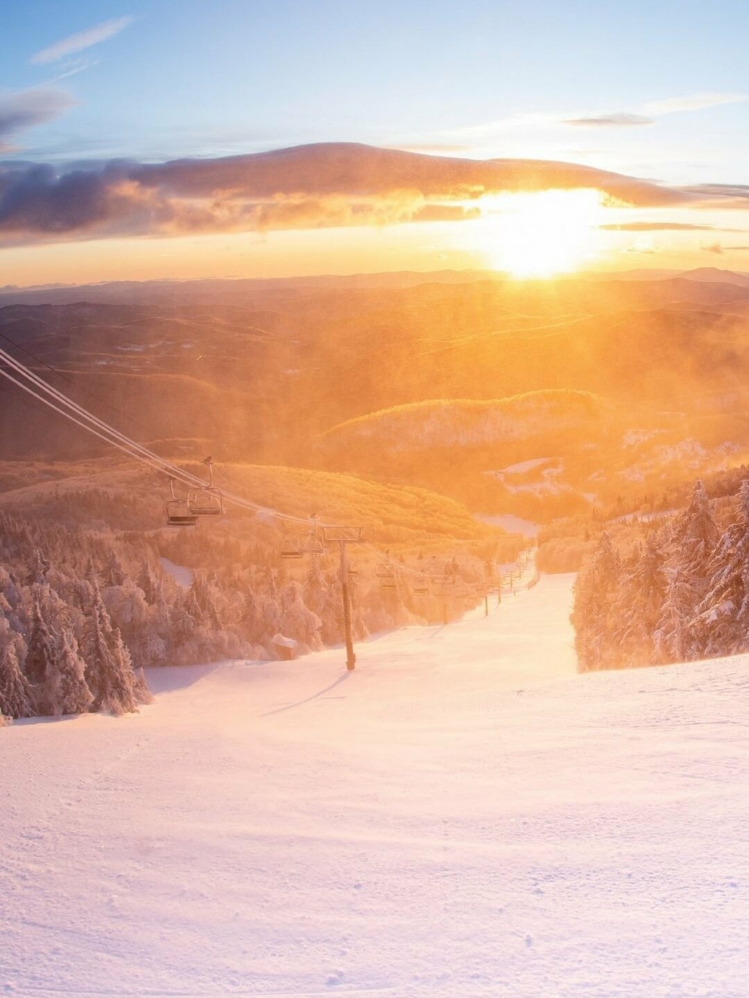 Sunrise over snowy mountains with ski lifts in Killington, Vermont.