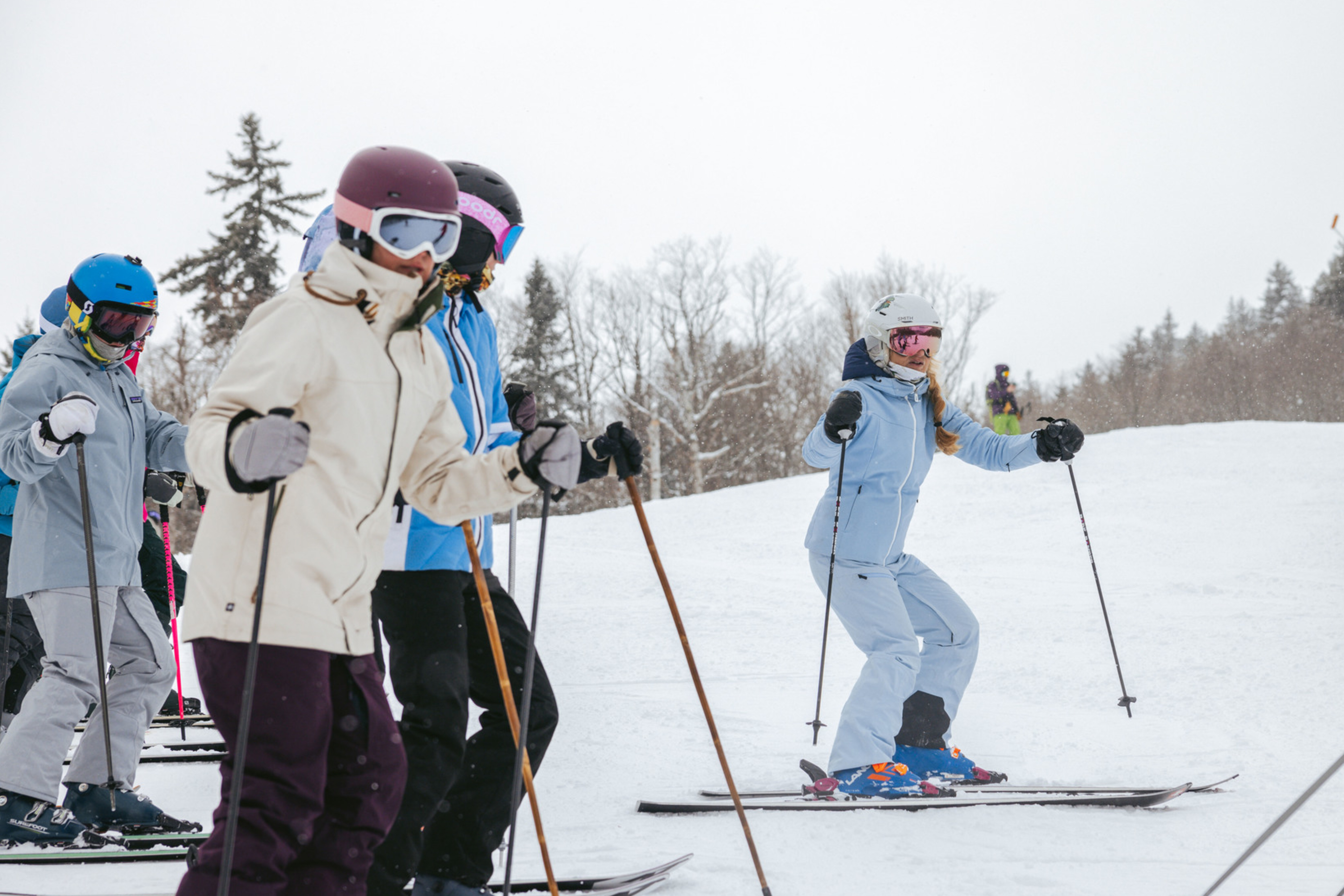 A group of skiers in winter gear practicing on a snowy slope.