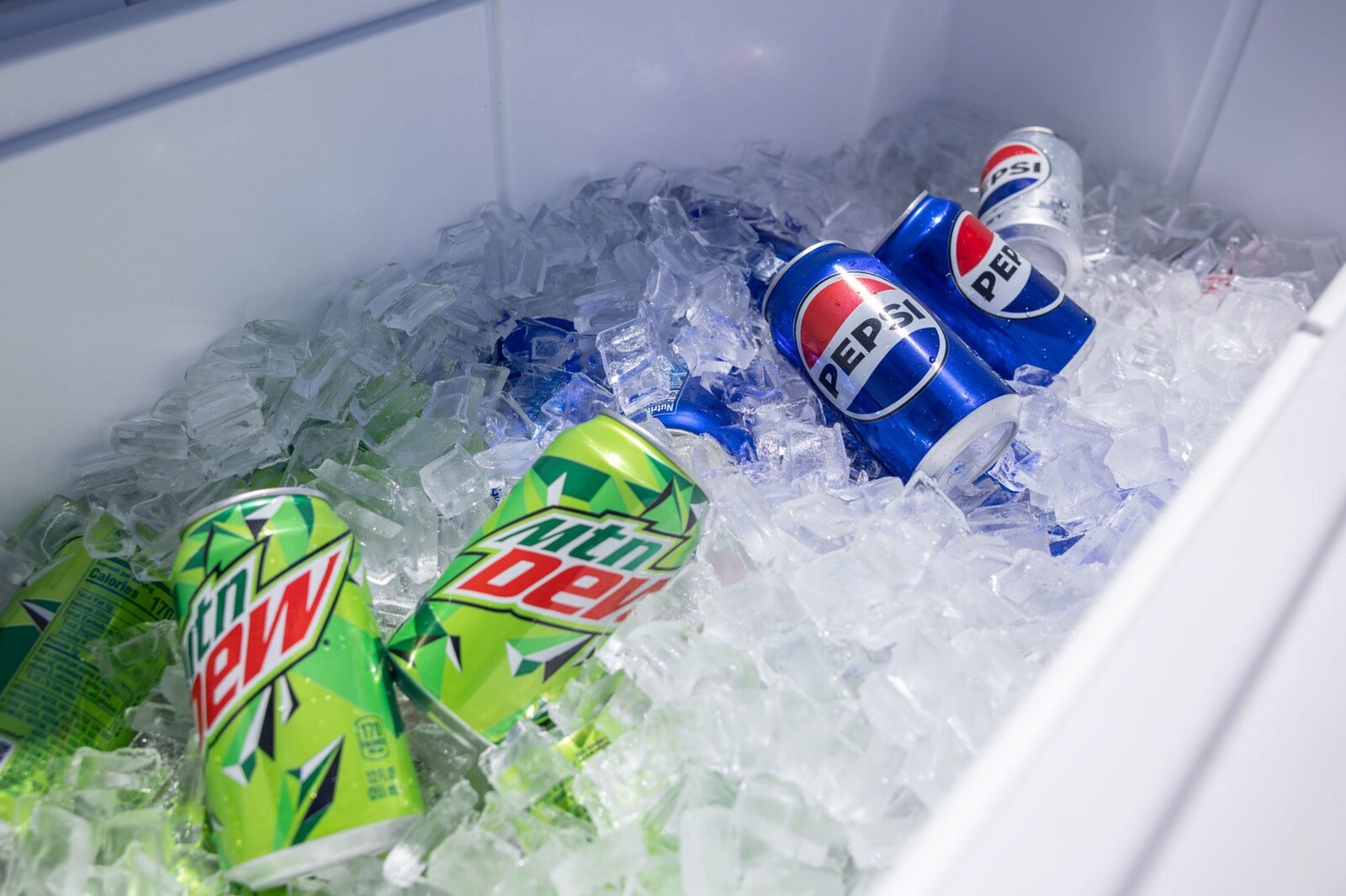 Cans of Mountain Dew and Pepsi on ice in a cooler.