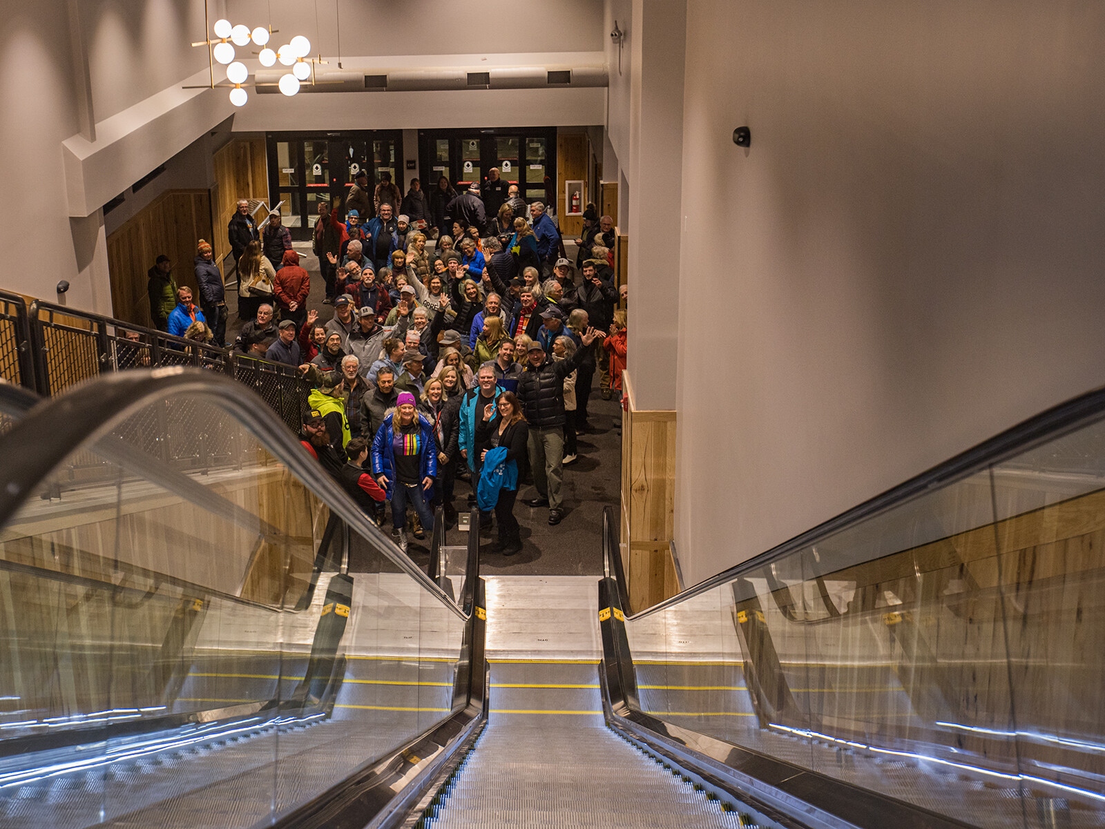 View from above an escalator showing a large crowd gathered indoors.