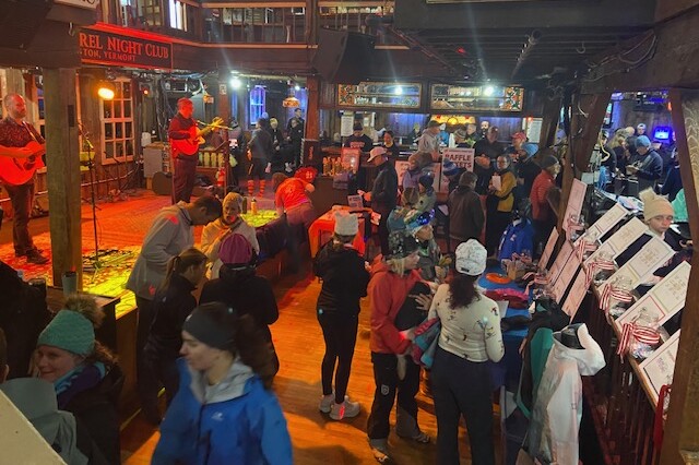 Crowded venue with live music, activities, and raffle displays at a night club event.