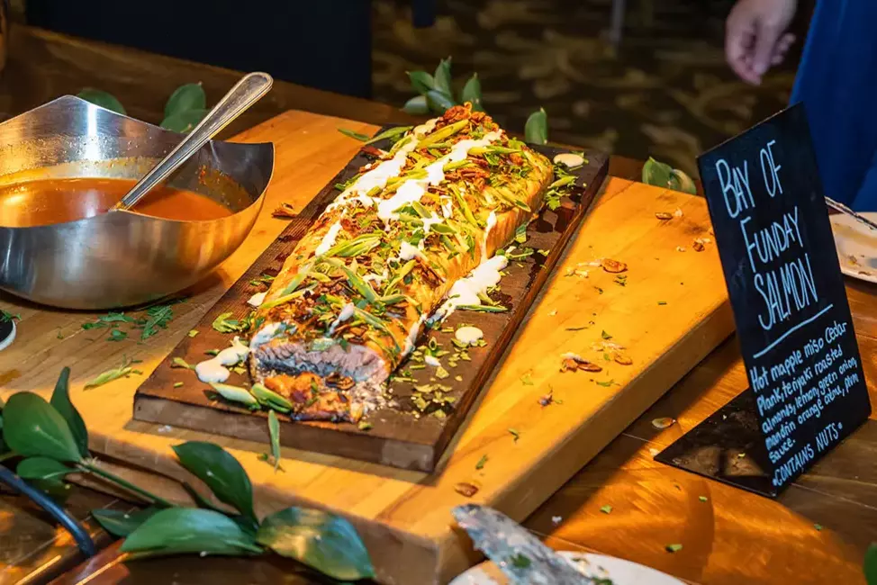 Platter of salmon topped with herbs, served with sauce and labeled "Bay of Funday Salmon."