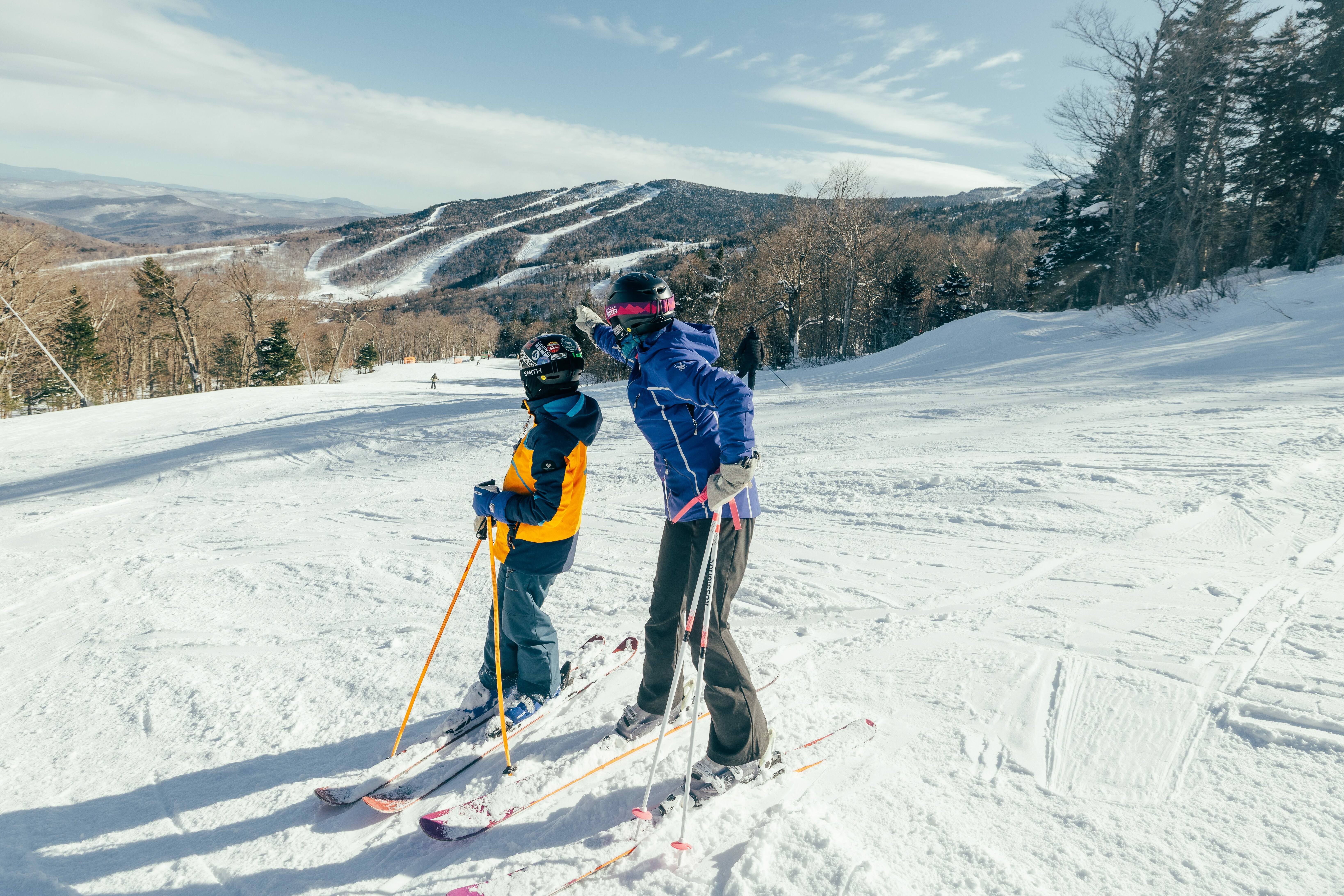 Two skiers on a snowy slope, enjoying the mountain view and discussing the scene.