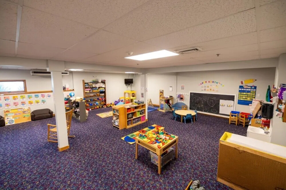 Bright, colorful preschool classroom with toys, learning materials, and a chalkboard.