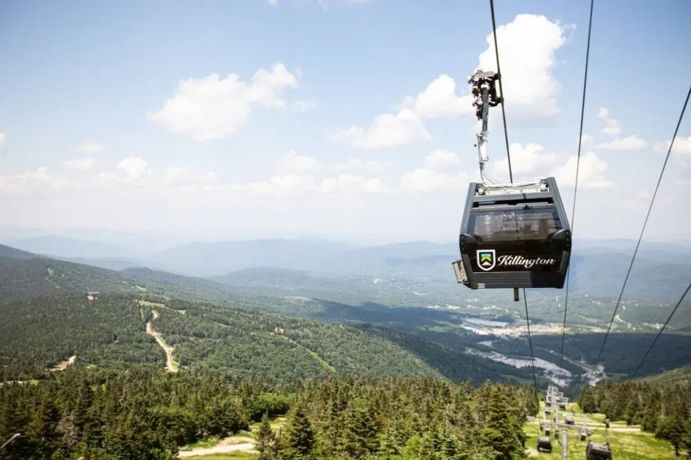 A gondola lifts over a mountainous landscape with green forests and blue skies at Killington Mountain Resort