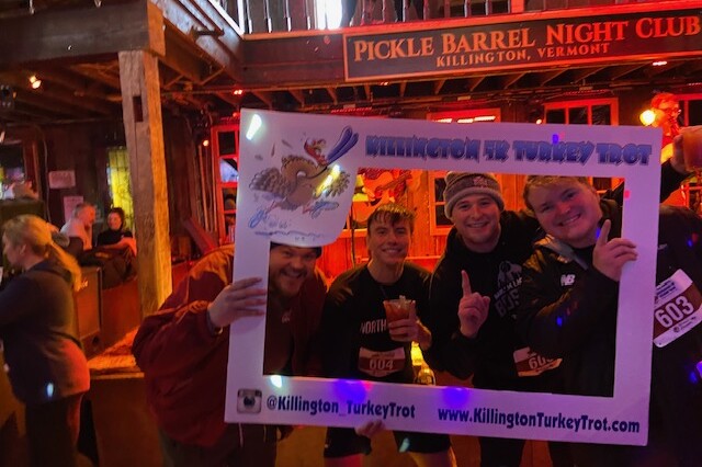 Four participants pose with a fun photo frame at the Killington Turkey Trot event.