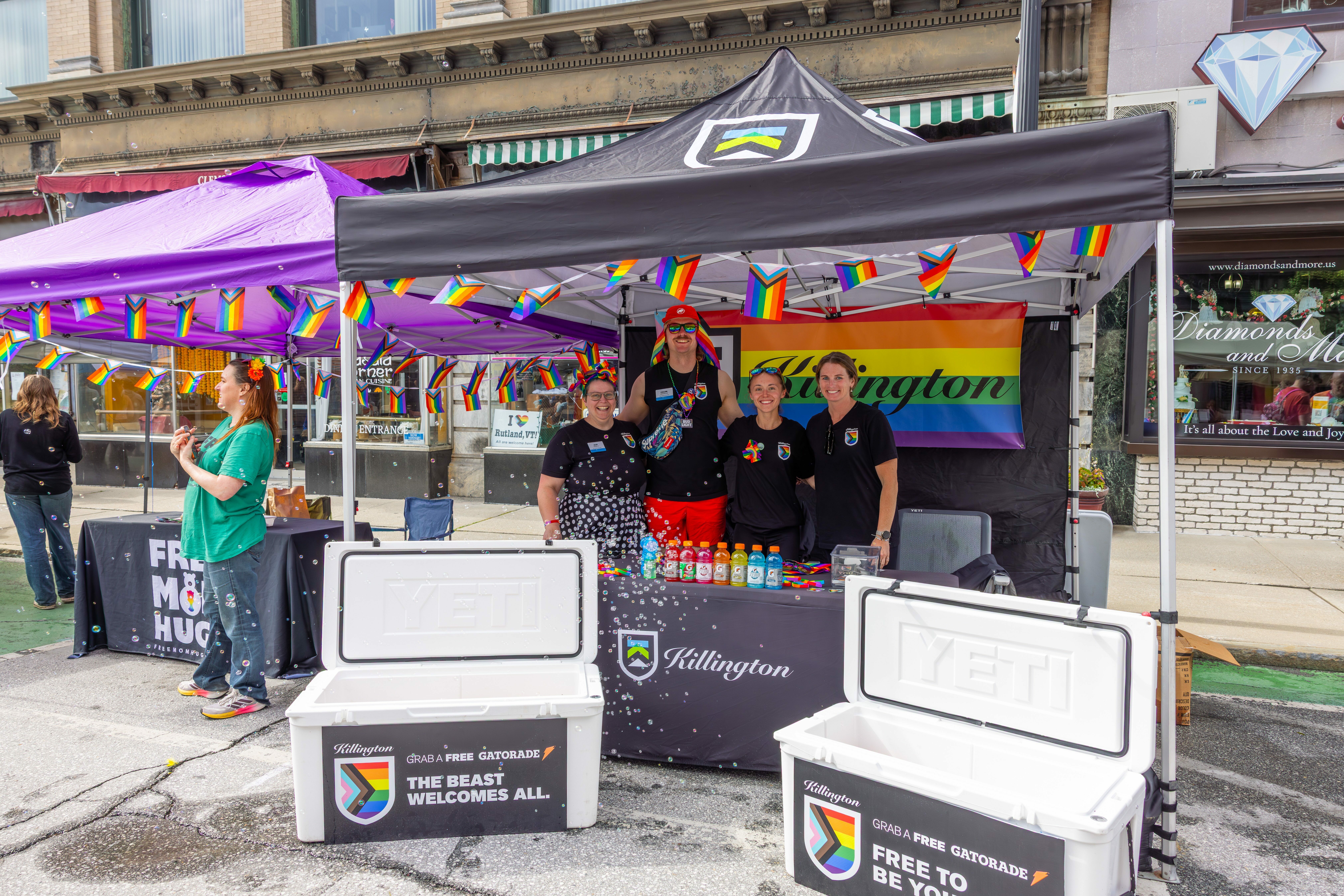 Employees pose at booth setup at pride festival