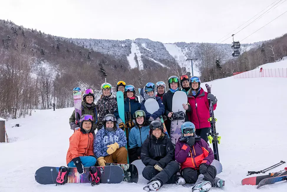 Group of skiers and snowboarders posing together on a snowy mountain slope.